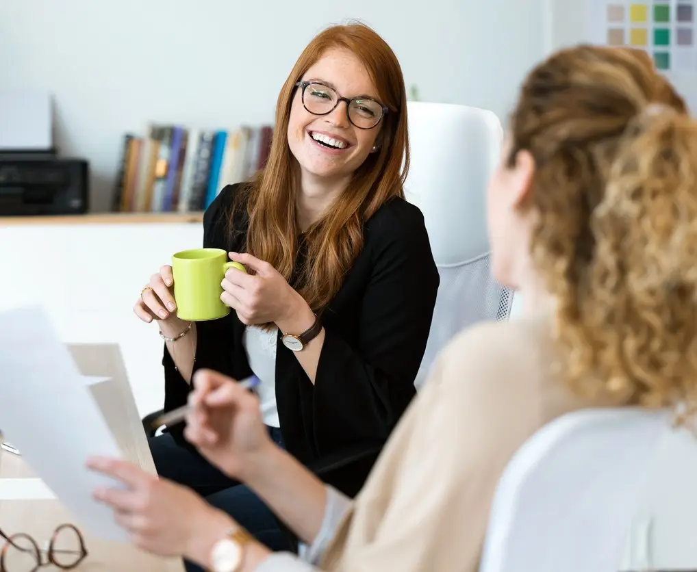 Shot of two pretty young business woman relaxing one moment while drinking coffee in the office.